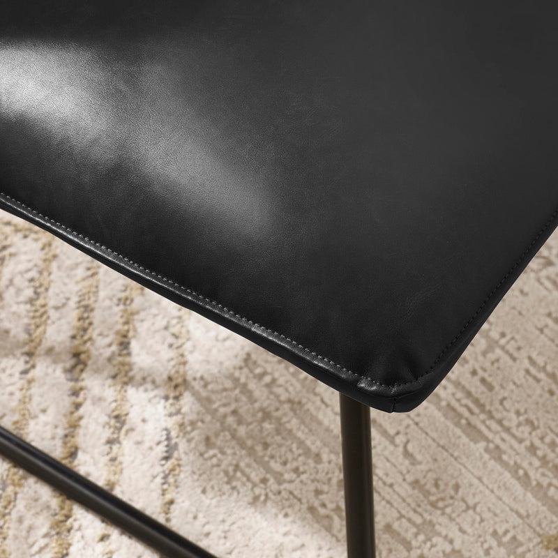 Close-up of a black leather chair on a textured beige surface