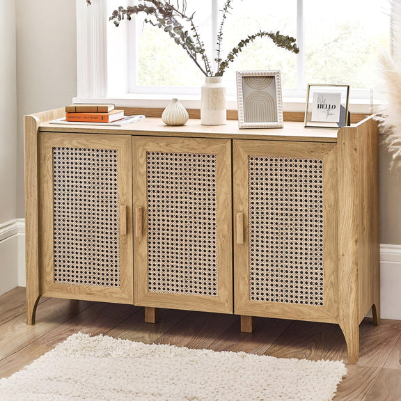 Wooden sideboard with wicker doors in a room with a window and decor items.