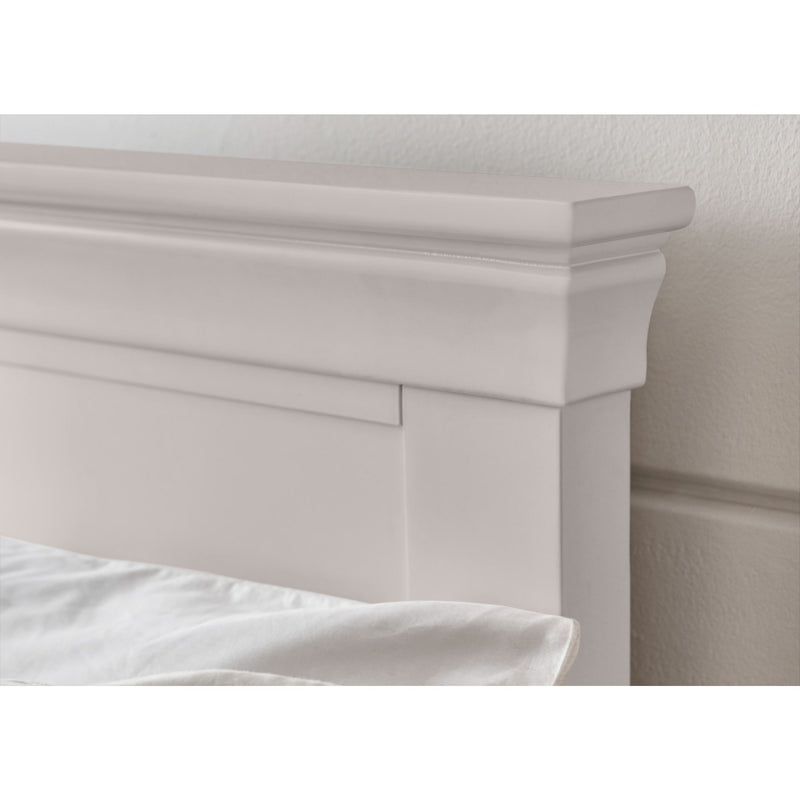 Close-up of a white wooden headboard with a neutral wall background