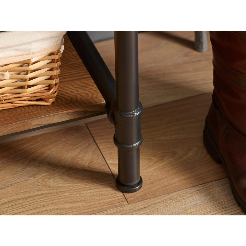 Close-up of a metal leg on a wooden floor with a woven basket and brown boot in the background.