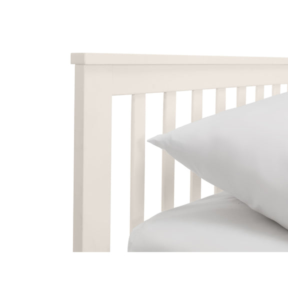 White wooden crib with a white pillow on a white background