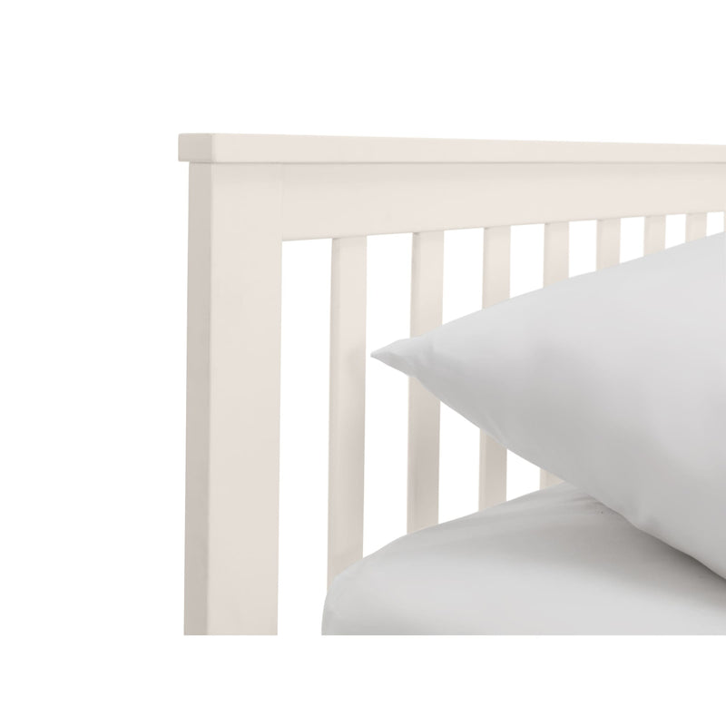 White wooden crib with a white pillow on a white background