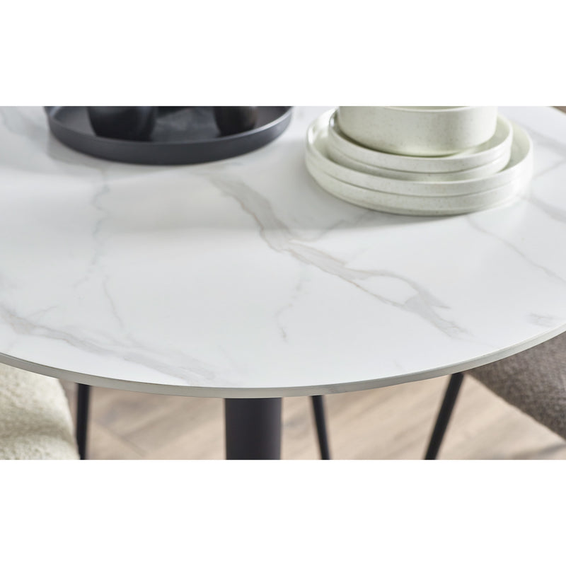 Round glass table with black legs and white plates on a neutral background