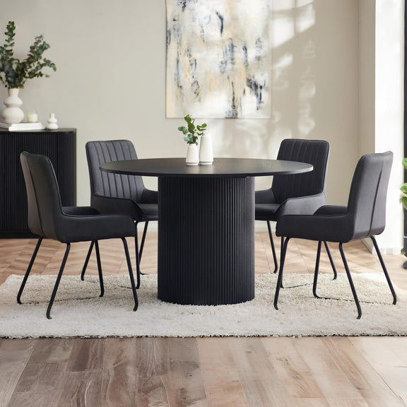 Dining room with a black round table and four gray chairs on a light wooden floor.