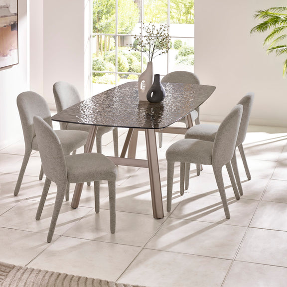 Dining table with six chairs in a bright room with large windows.