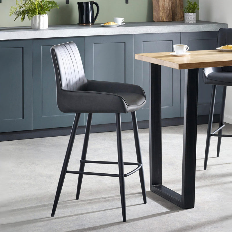 Modern kitchen with gray bar stools and a wooden table.
