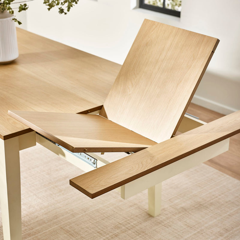 Wooden dining table with a chair being extended in a bright room.