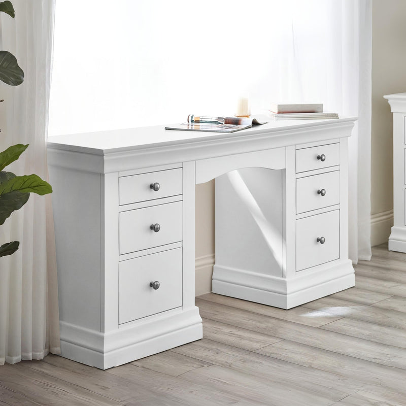 White desk with multiple drawers in a room with light wood flooring and white walls.