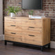 Wooden dresser with black handles against a brick wall