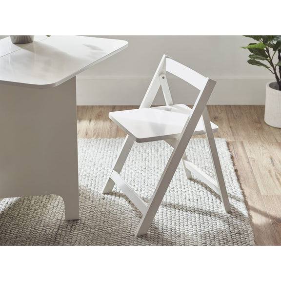 White folding chair next to a white table on a wooden floor with a rug