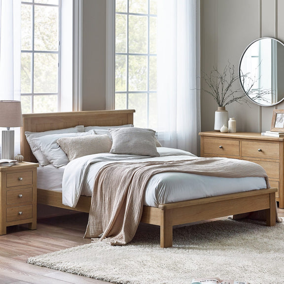 Wooden bed in a well-lit bedroom with light-colored walls and decor.