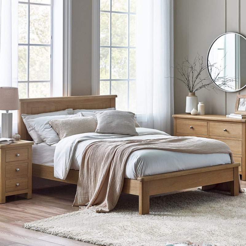 Wooden bed in a well-lit bedroom with light-colored walls and decor.