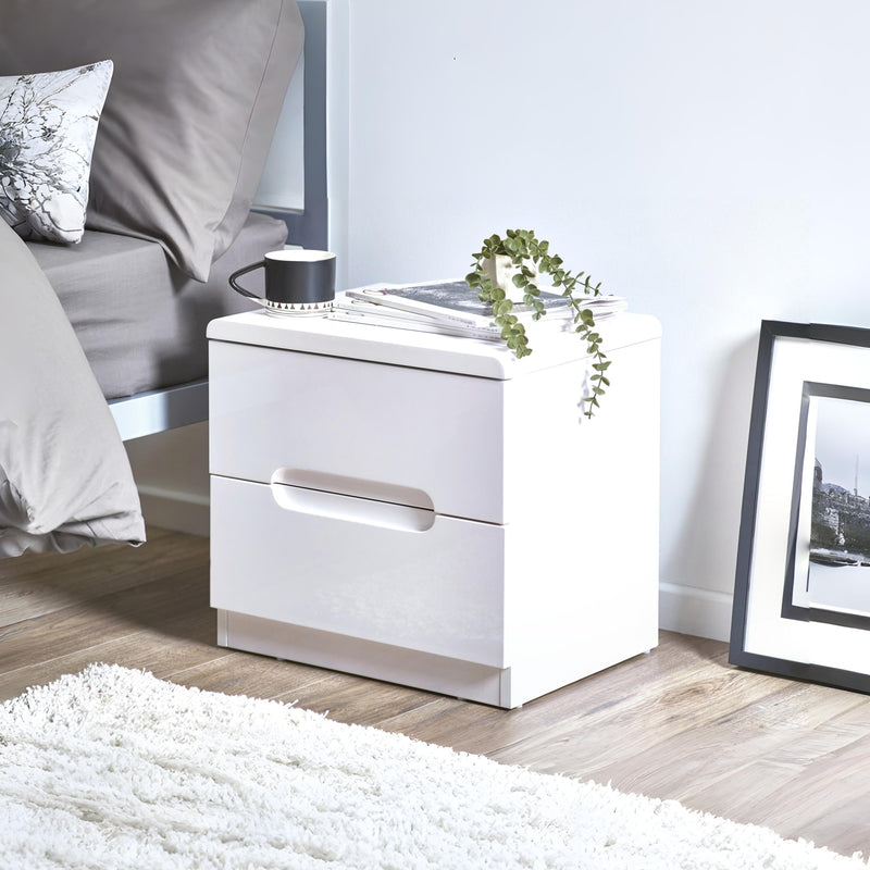 White nightstand with a lamp and plant in a bedroom setting