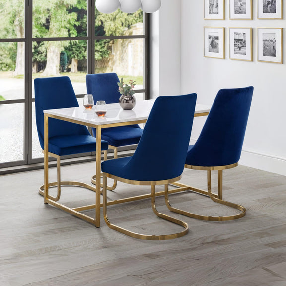 Dining room with blue chairs and a white table near large windows.