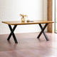 Wooden table with black metal legs in a room with wooden floor and white brick wall.