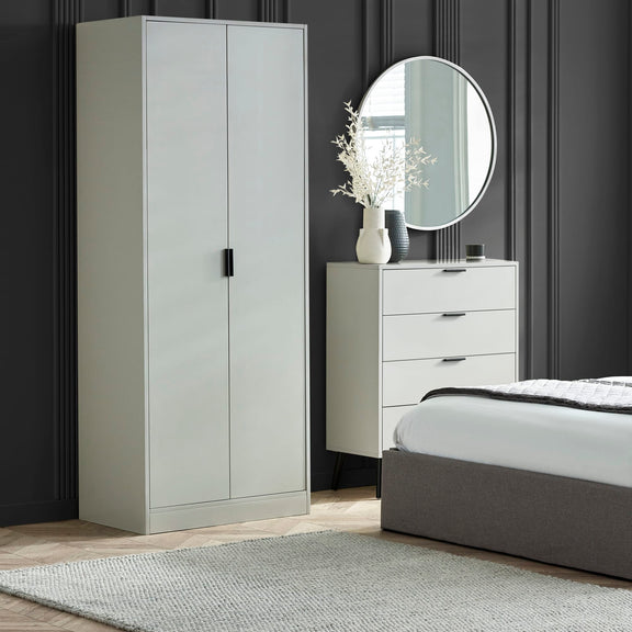 Gray wardrobe, dresser, and bed in a bedroom setting with a round mirror above the dresser.