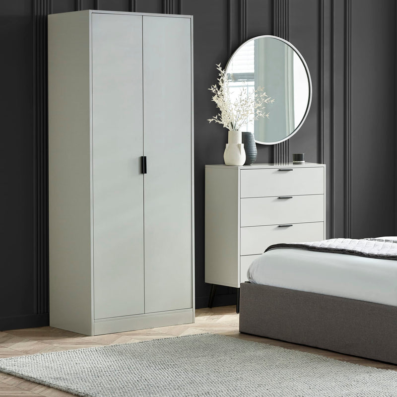 Gray wardrobe, dresser, and bed in a bedroom setting with a round mirror above the dresser.
