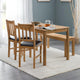 Wooden dining set with table, chairs, and bench in a room with gray walls and white curtains.