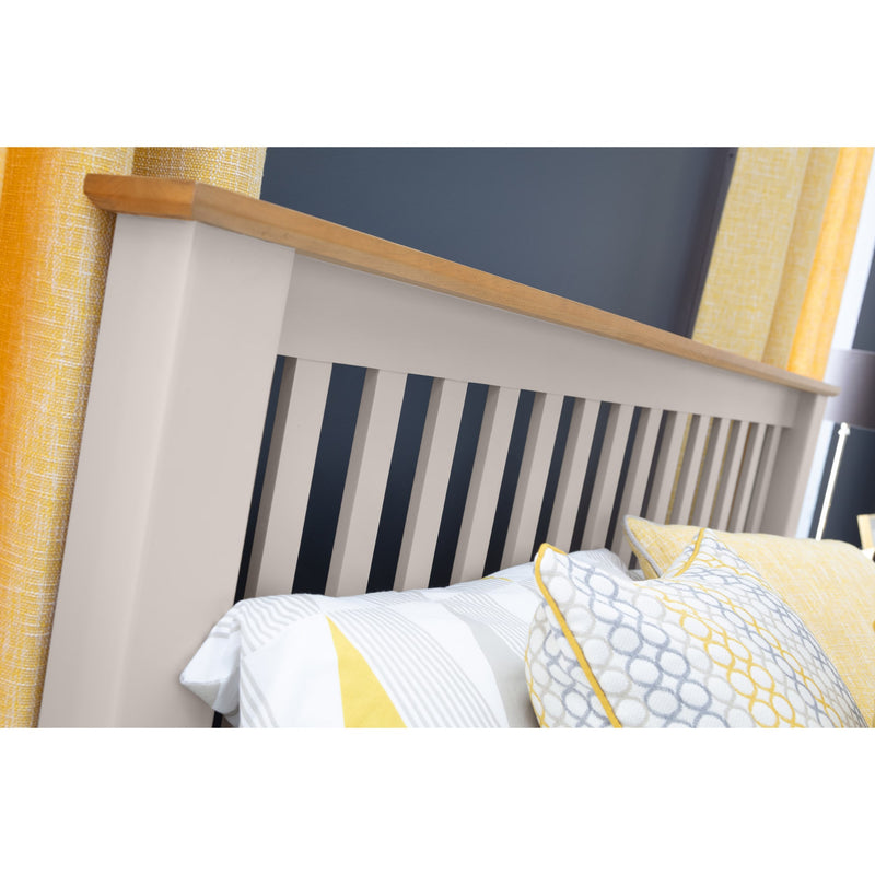 Close-up of a bed with a wooden headboard and yellow and white bedding.