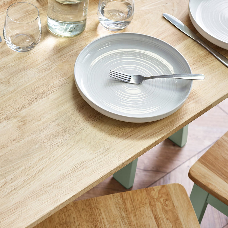 Dining table setup with a white plate, fork, and glasses on a wooden surface.