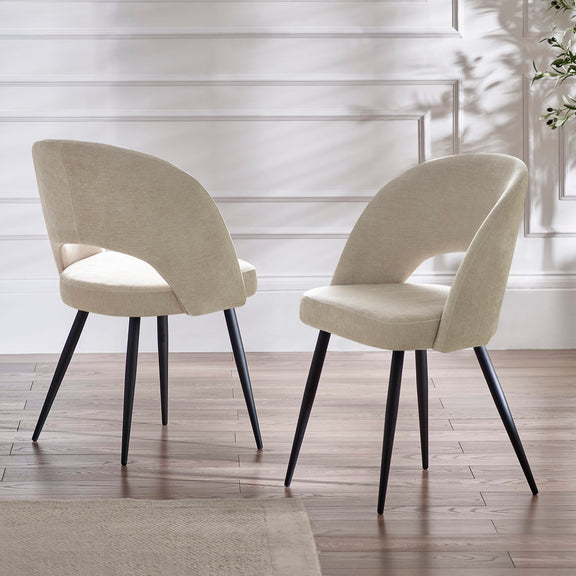 Two beige chairs with black legs on a wooden floor.
