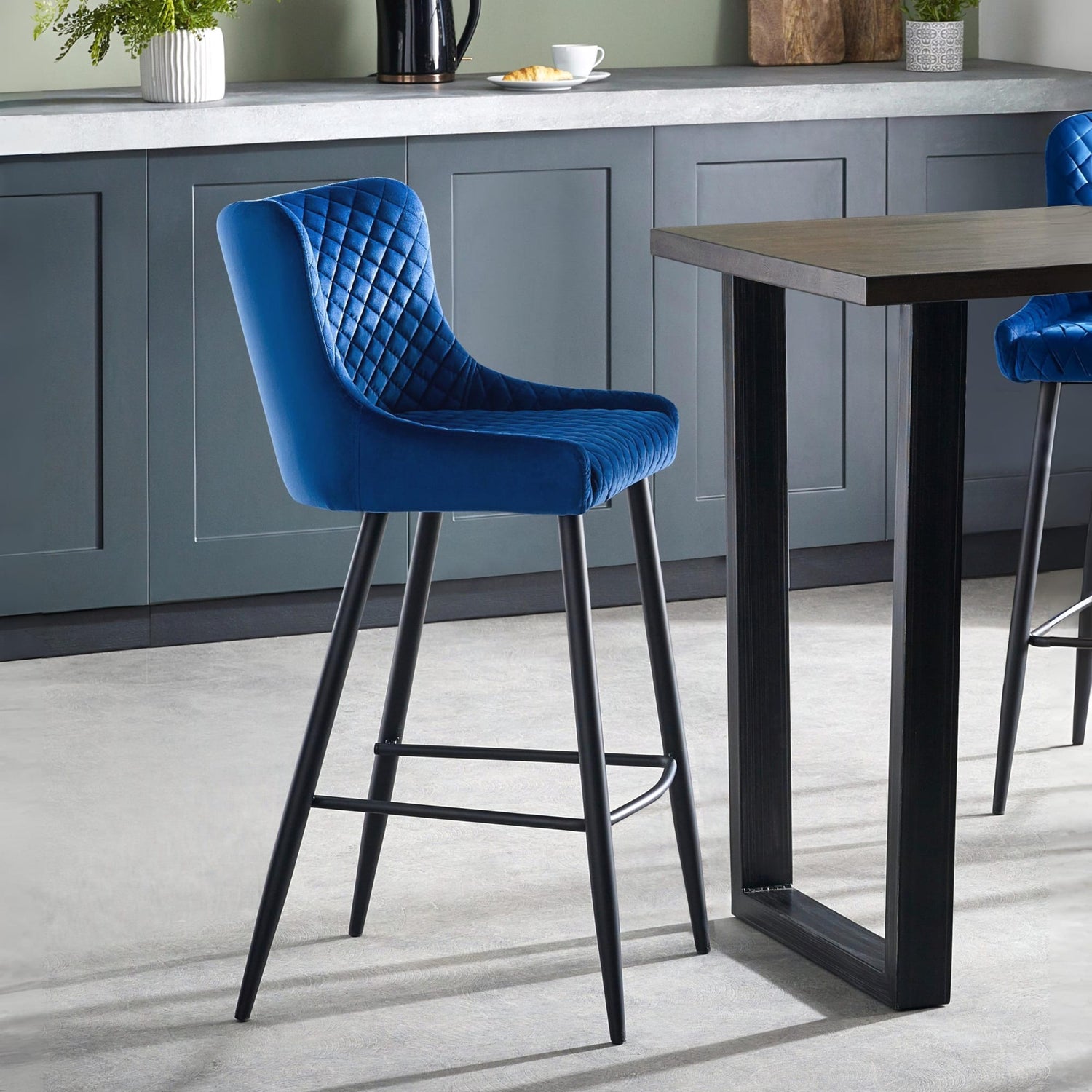 Blue bar stool in a kitchen setting with a table and cabinets.