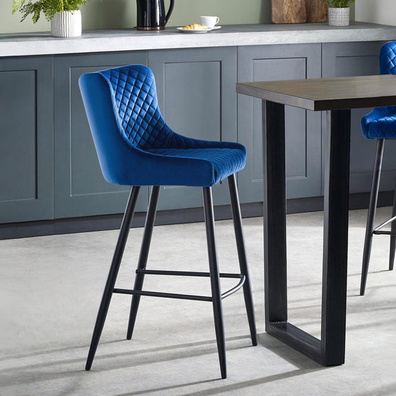 Blue bar stool in a kitchen setting with a table and cabinets.