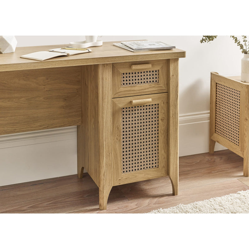 Wooden desk with a rattan-patterned drawer in a room setting.