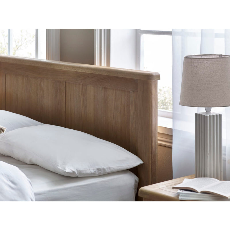 Bedroom with wooden headboard, white pillows, and a lamp on a nightstand.