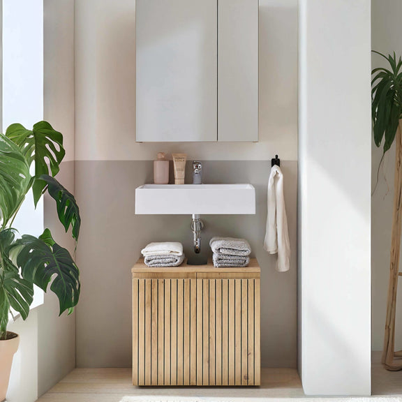 Bathroom with wooden vanity, white sink, and towels.