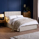 Neatly made bed with beige headboard and bedding in a bedroom setting.