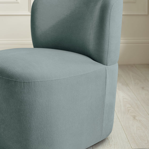 Teal armchair in a room with light-colored walls and floor.