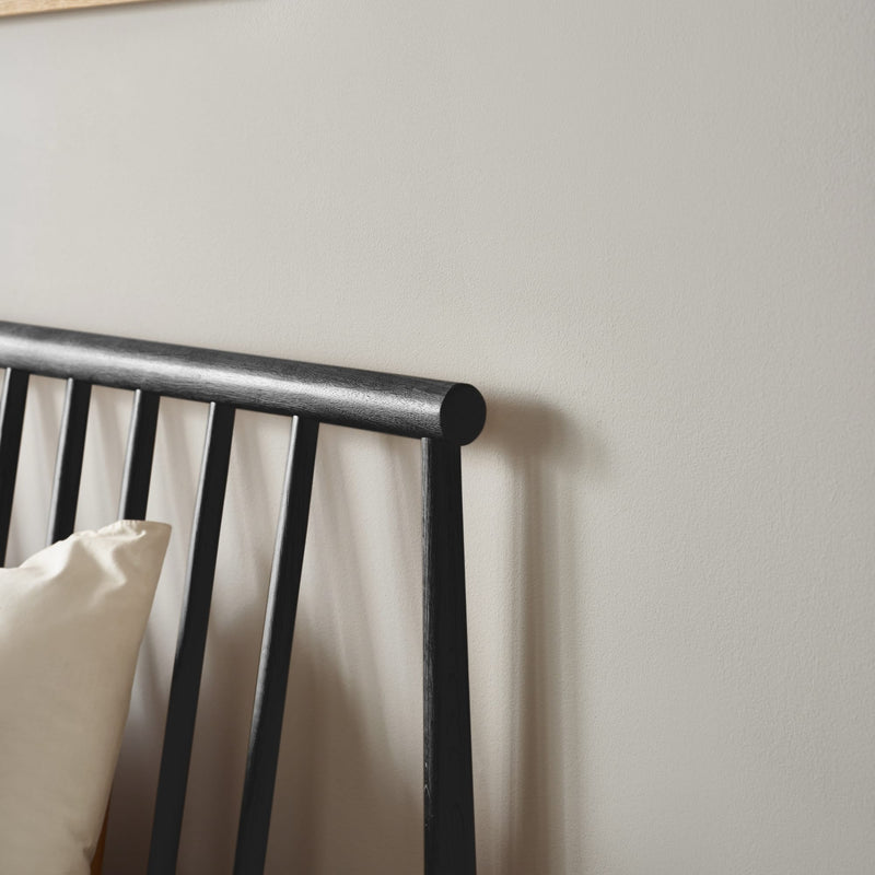 Black metal bed frame with white pillows against a light gray wall