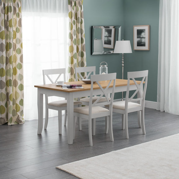 Dining room with a wooden table and white chairs against a light blue wall.
