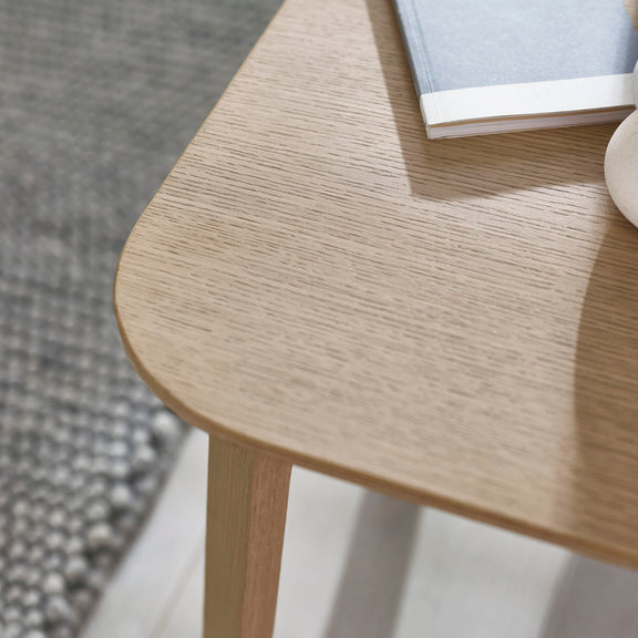 Wooden side table with a book on top, blurred background