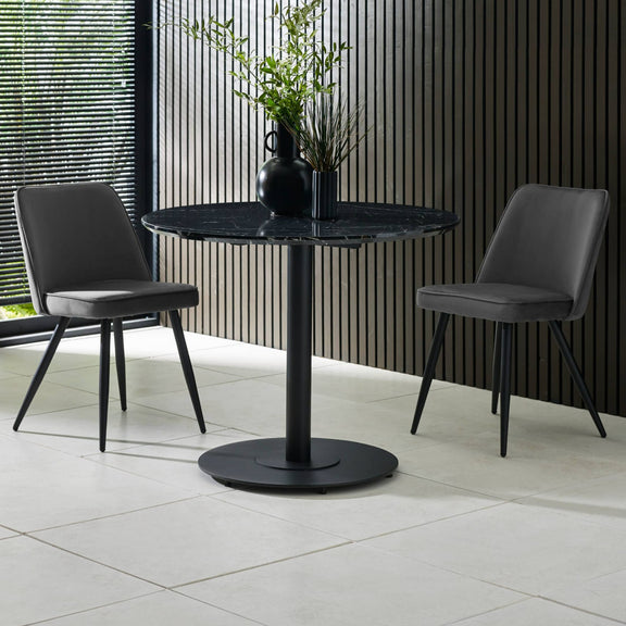 Black marble table with two gray chairs in a modern indoor setting.