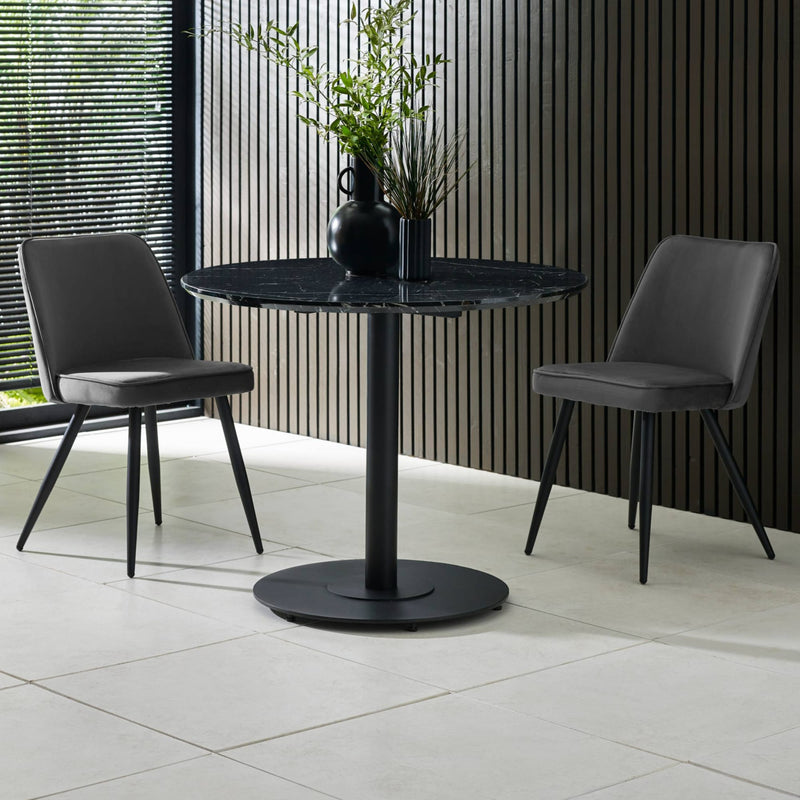 Black marble table with two gray chairs in a modern indoor setting.