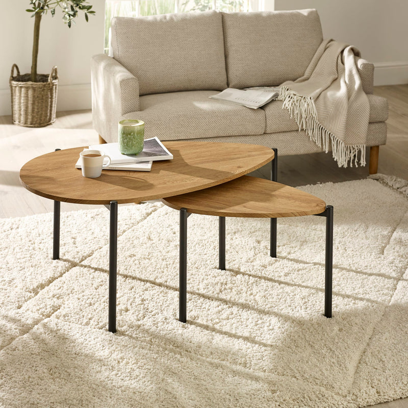Nest of wooden coffee tables in a living room setting with a sofa and decor items.