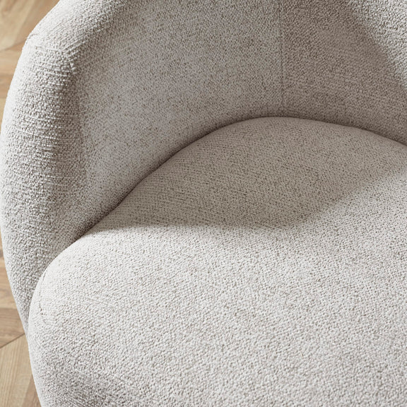 Close-up of a textured beige chair with a wooden floor in the background