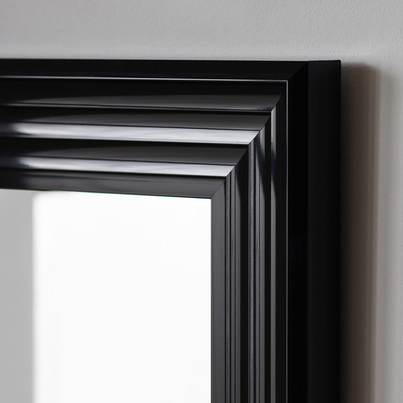 Close-up of a black framed mirror on a gray wall