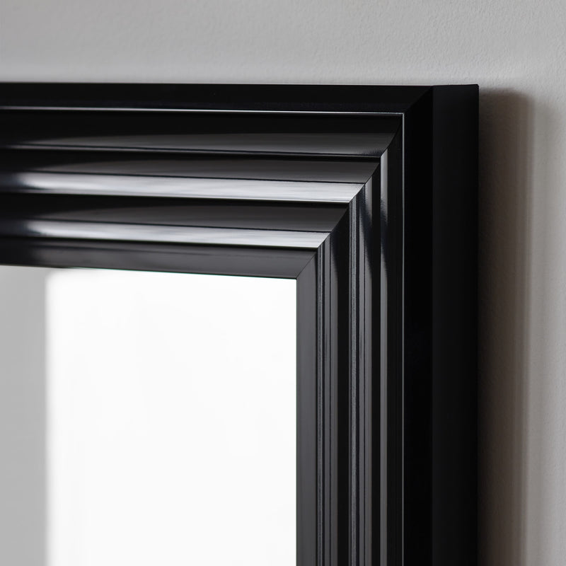 Close-up of a black framed mirror on a gray wall