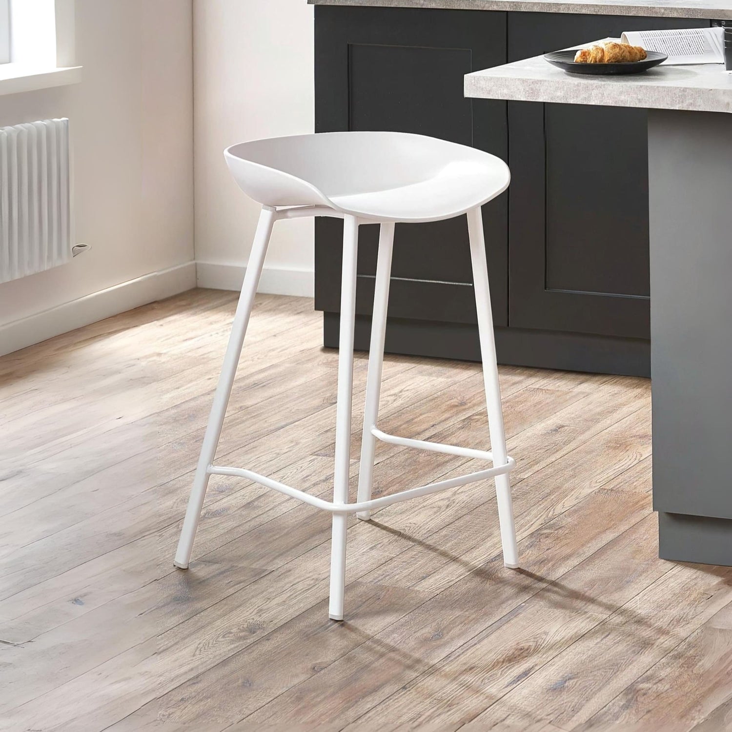 White bar stool on a wooden floor in a kitchen setting