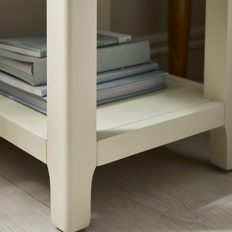 Stack of books on a white wooden shelf with a neutral background