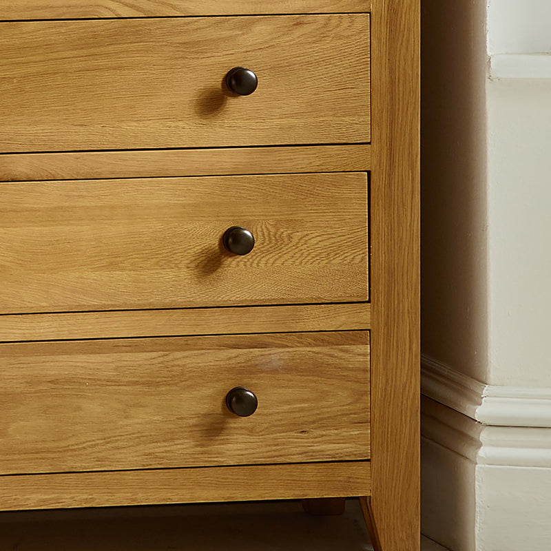 Wooden dresser with three drawers and metal knobs on a white background
