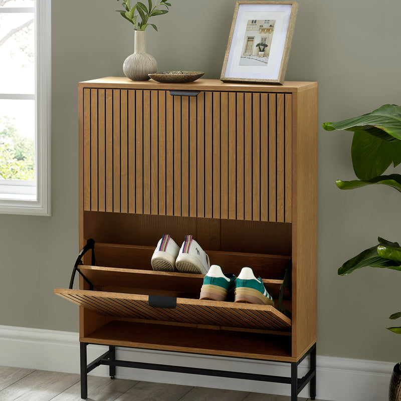 Wooden shoe cabinet with open door showing shoes, placed against a wall with decor items.