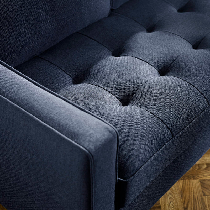 Close-up of a dark blue upholstered chair with tufted backrest.