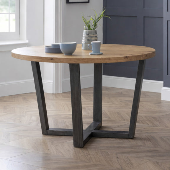 Wooden dining table with metal legs in a room with a window and wall.