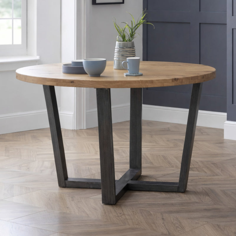 Wooden dining table with metal legs in a room with a window and wall.
