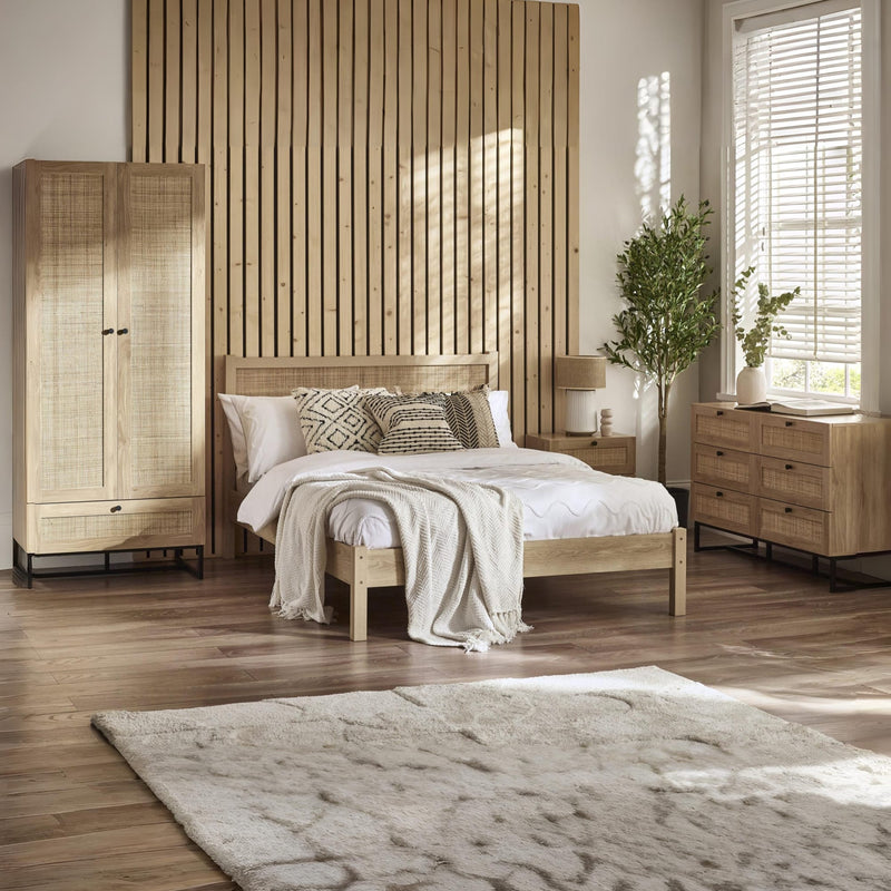 Wooden bedroom furniture set with bed, wardrobe, and dresser in a room with wooden flooring and slatted wall.