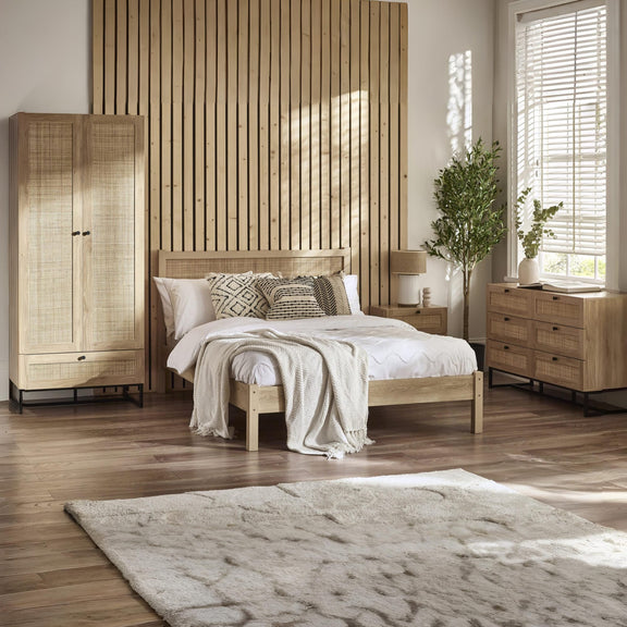 Wooden bedroom furniture set with bed, wardrobe, and dresser in a room with wooden flooring and slatted wall.